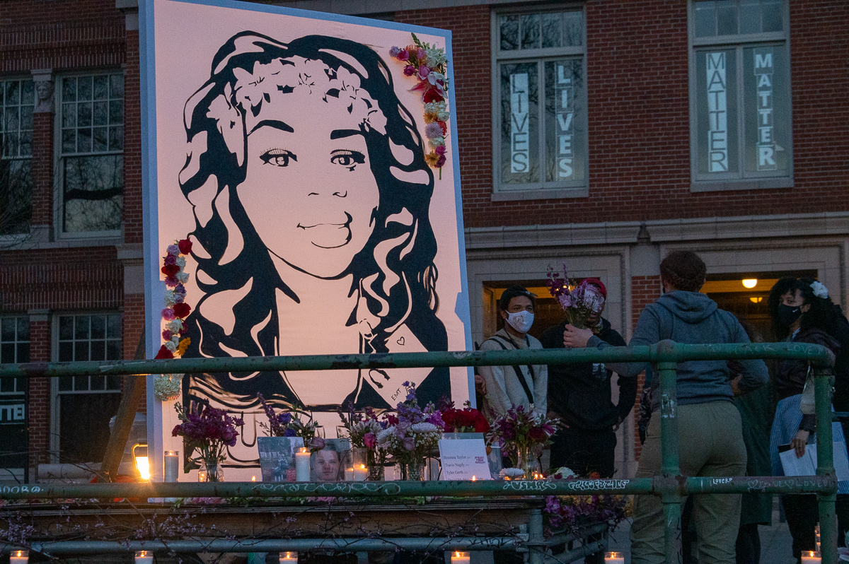 a mural of breonna taylor is lit by candles at a vigil in Portland, Oregon, on the anniversary of her shooting death in 2021
