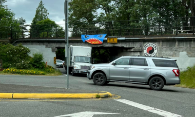 The pedestrian rails to trail bridge in Kirkland Washington that goes over Kirkland Avenue, and has a banner of eyes and an open mouth with the words I eat trucks with a panel truck stuck under the bridge