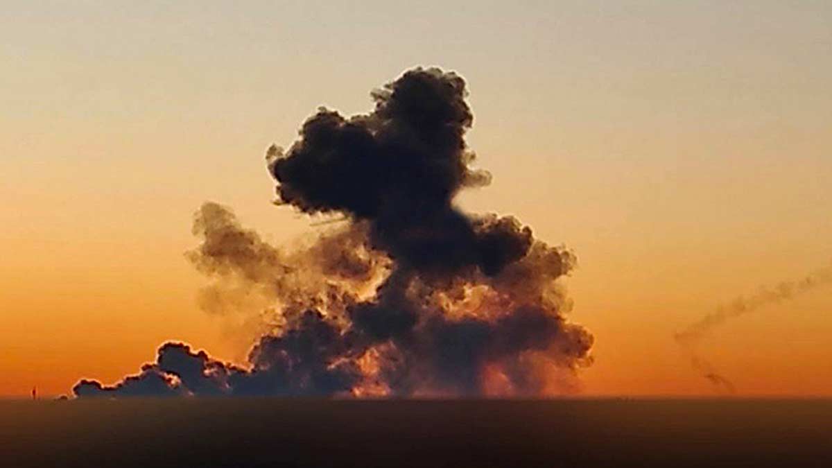 smoke rises from Kanatove air force base in Kirovohrad, Ukraine. The smoke is backlit by an orange sky as the sun is rising, with black clouds rolling in the wind