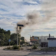 The sun rises over russian occupied lysychansk with black smoke rising on the horizon - the view looks at an intersection in the city with debris in the road and damaged buildings
