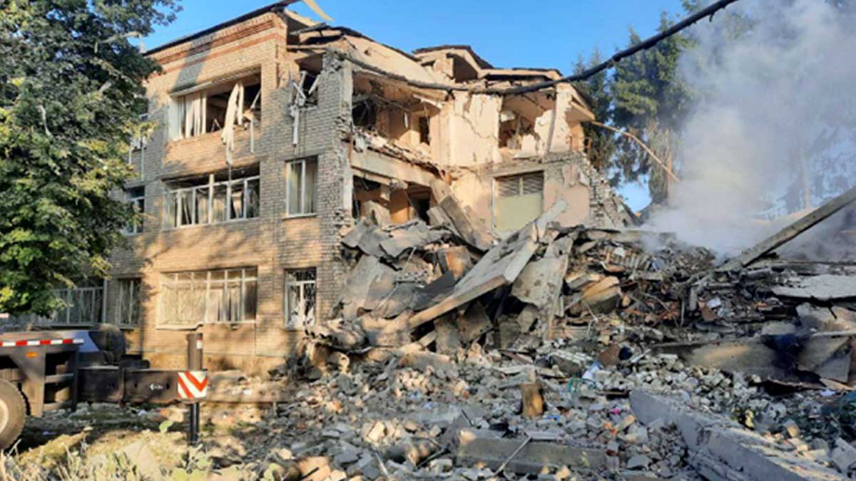 A three story school building made of tan brick is heavily damaged and partially collapsed - there are no people in the picture