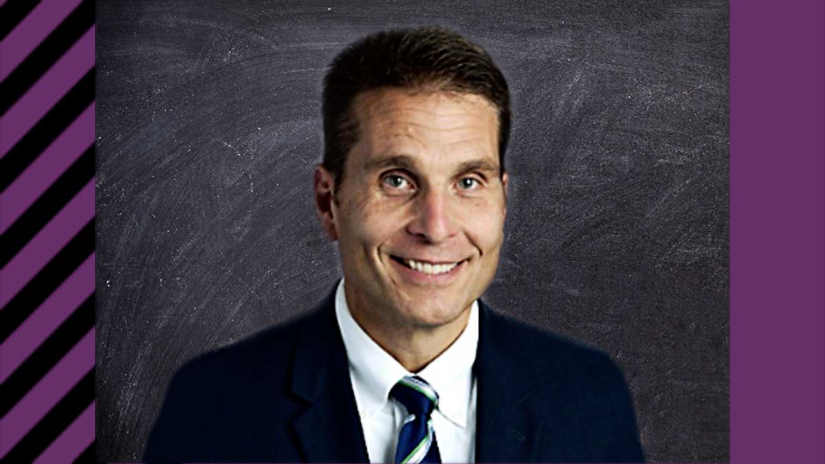 A headshot picture of former Monroe School District Superintendent Justin Blasko, wearing a navy blue suit, white shirt, and blue, white, and green stripped tie, he is smiling in the picture