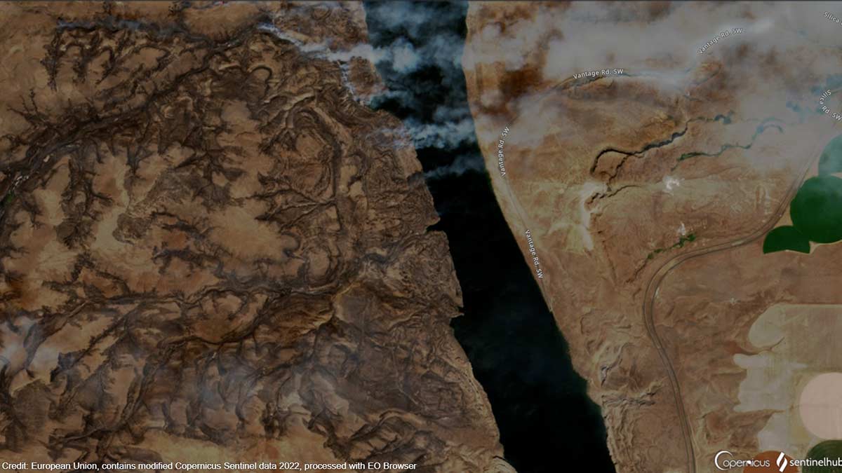 An enhanced color satellite image showing the wildfire north of Vantage, Washington from space, with the Columbia River bisecting the image north to south. The main fire is burning on the west bank of the river