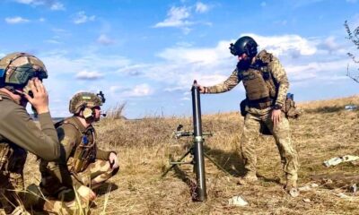 three ukrainian soldiers are in a field of dry wheat firing a mortar during the daytime