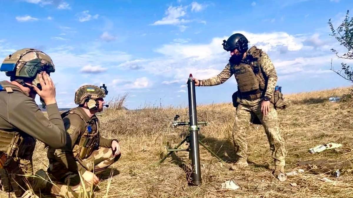 three ukrainian soldiers are in a field of dry wheat firing a mortar during the daytime