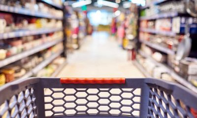 An out of focus grocery store with a shopping cart in the foreground