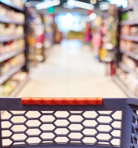 An out of focus grocery store with a shopping cart in the foreground