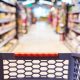 An out of focus grocery store with a shopping cart in the foreground