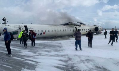 Delta Airlines CJR-900 after crashing in Toronto with people walking away.