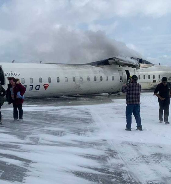 Delta Airlines CJR-900 after crashing in Toronto with people walking away.