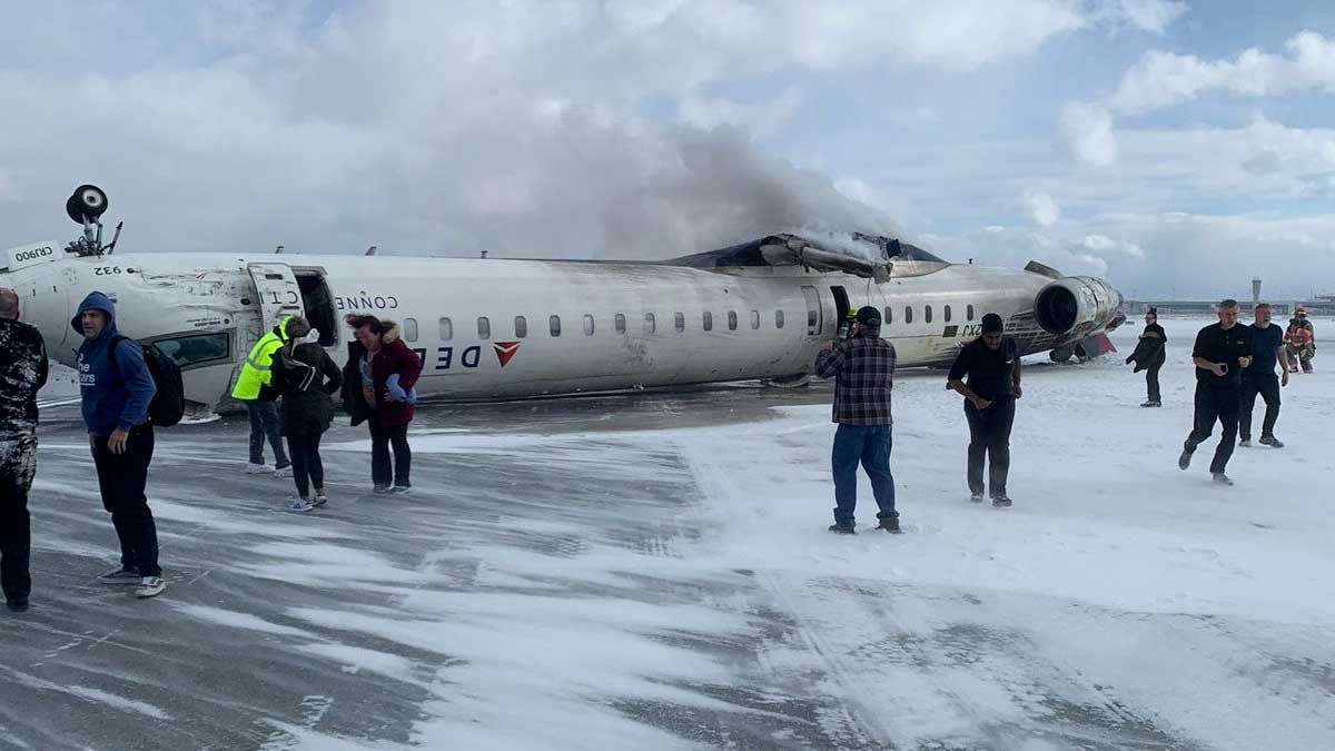 Delta Airlines CJR-900 after crashing in Toronto with people walking away.