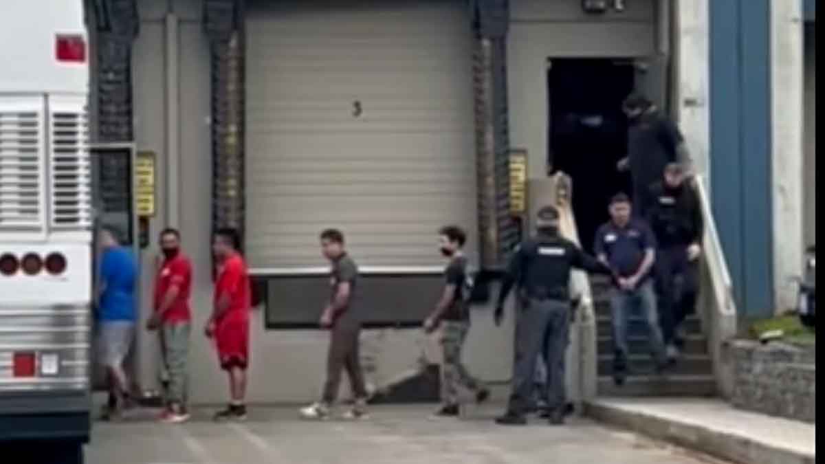 Allegedly undocumented immigrants in handcuffs being loaded onto a bus in Kent, Washington