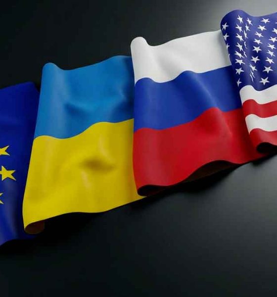 Flags of the European Union, Ukraine, Russia, and the United States lying on a table.
