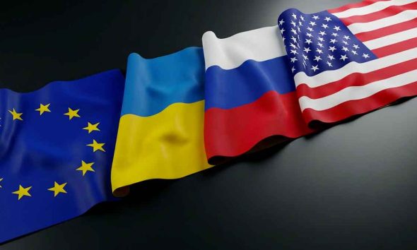 Flags of the European Union, Ukraine, Russia, and the United States lying on a table.