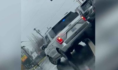 An unmarked federal ICE vehicles with police lights on a rainy street shown on a Dutch angle