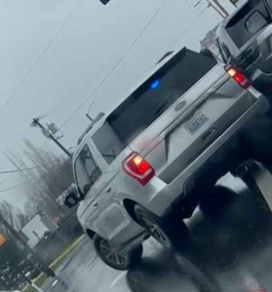 An unmarked federal ICE vehicles with police lights on a rainy street shown on a Dutch angle