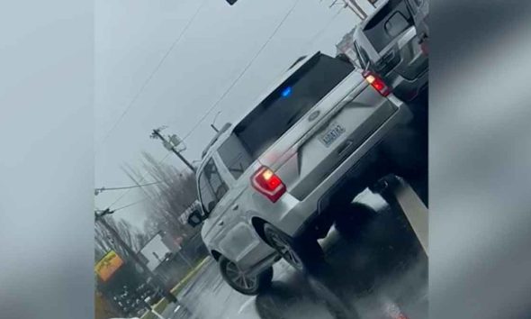 An unmarked federal ICE vehicles with police lights on a rainy street shown on a Dutch angle