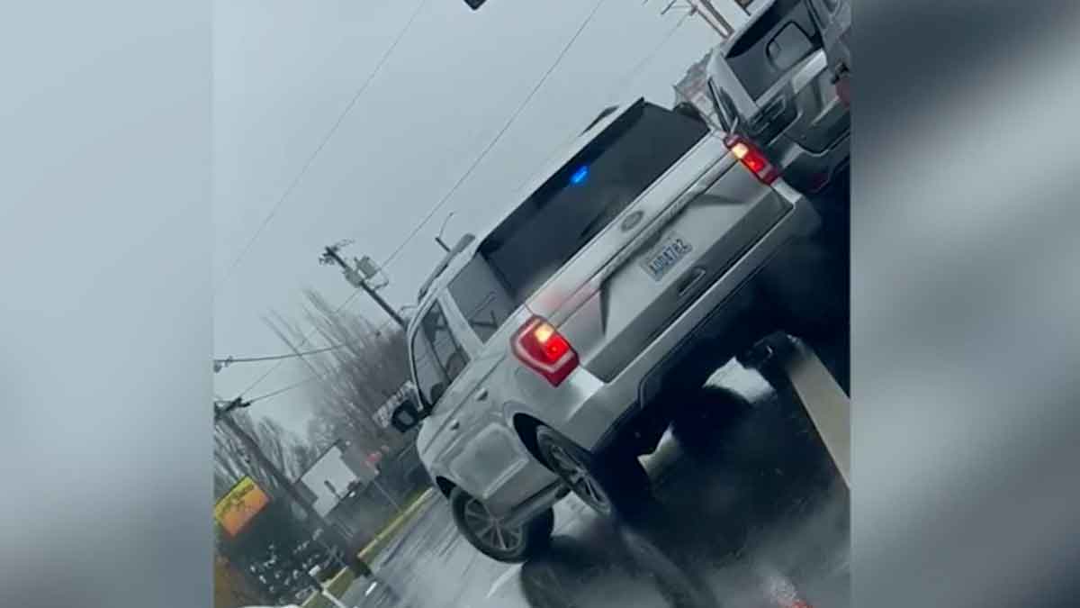 An unmarked federal ICE vehicles with police lights on a rainy street shown on a Dutch angle